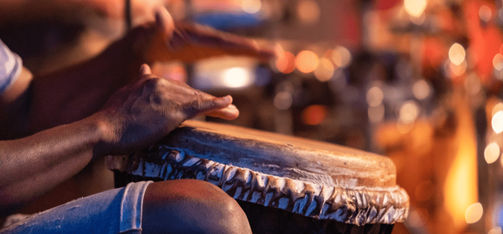 Closeup of person's hands drumming on a traditional drum.
