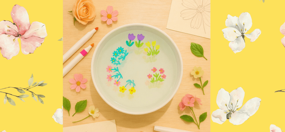 Ink flower illustrations floating in a bowl of water.