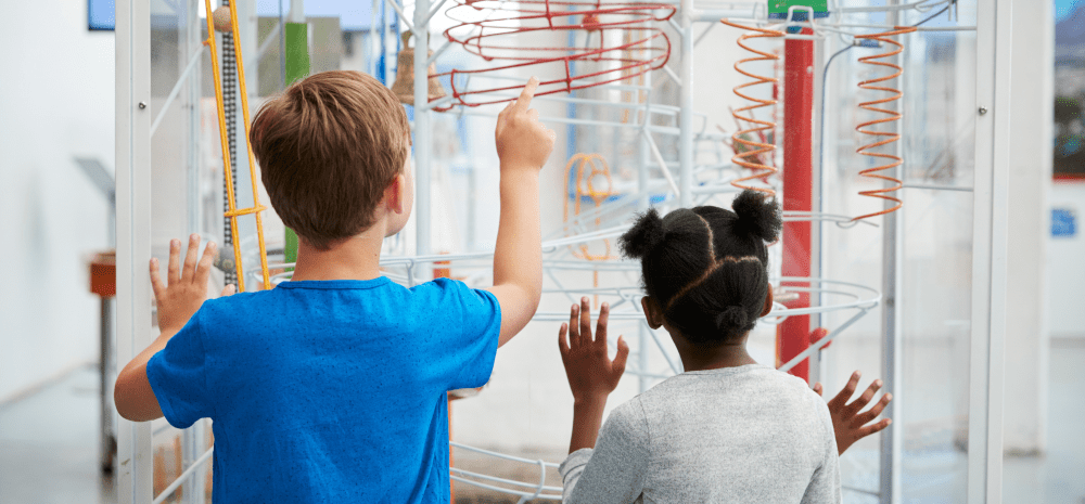 Two children looking at a ball obstical course. 