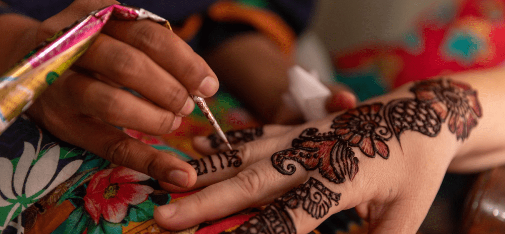 Image of one set of hands putting henna on another. 