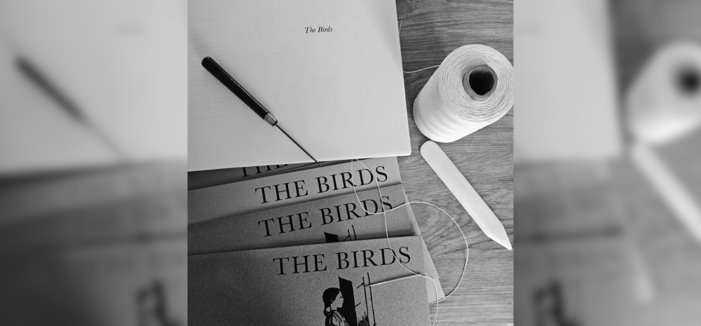 Assorted objects on a table; awl, bone folder, waxed thread