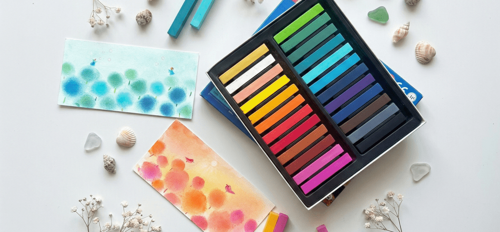 Artworks in pastel displayed against white background with small objects such as pastels, seashells and cut flowers.