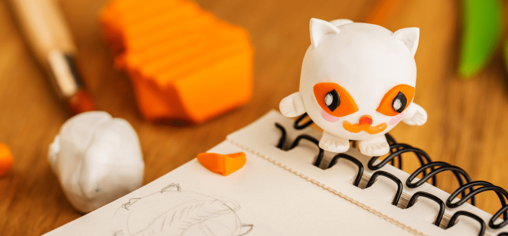 Clay sculpted objects on a table with notebook.