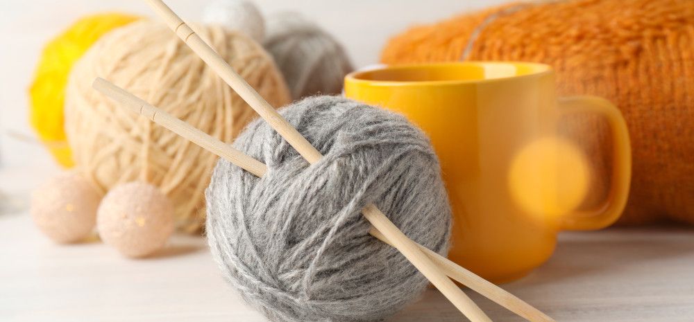 Balls of wool with knitting needles and a mug.