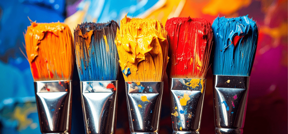 Five paint brushes side by side laden with colour.