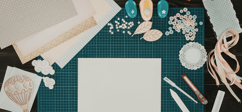 A cutting mat covered in paper, stencils and tools used to make cards. 
