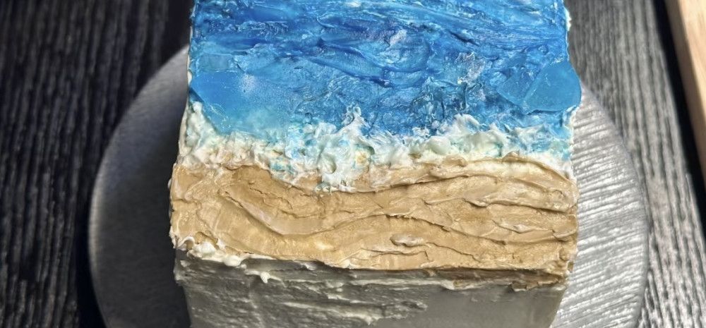 A cake decorated to look like a beach on a silver platter. 