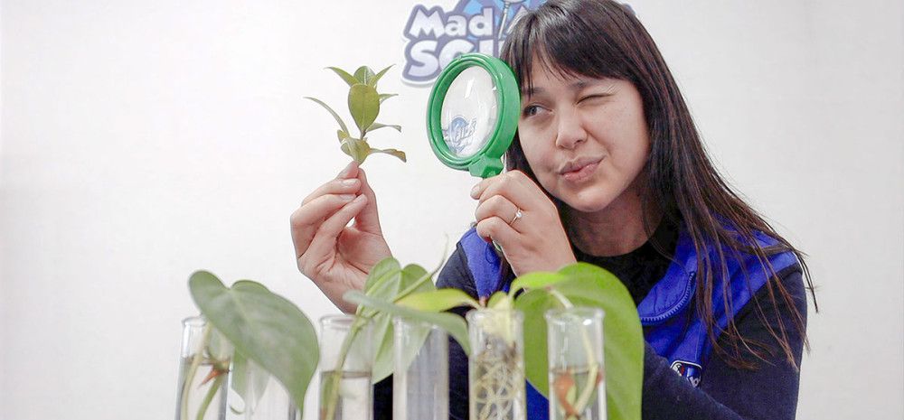 A woman looking through a magnifying glass at a plant.