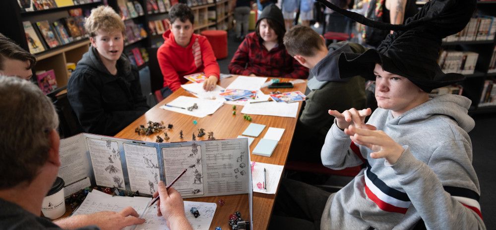 Group of young people playing dungeons and dragons around a table.
