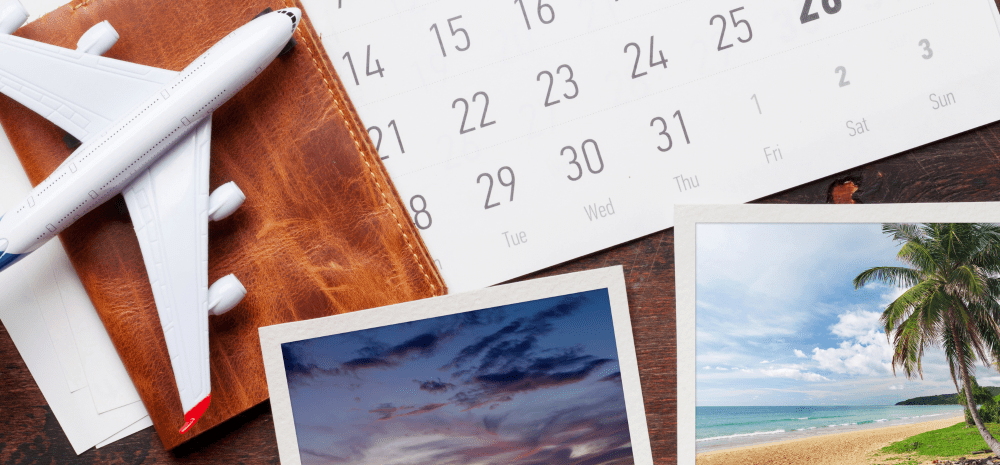 A travel-themed display featuring a calendar, printed photographs, a model airplane, and a notebook, highlighting memories, photography and planning.