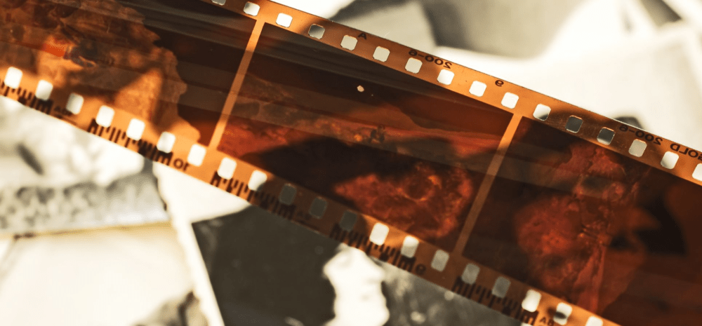 A close-up photograph of a photographic film strip displaying developed images against a softly blurred background.