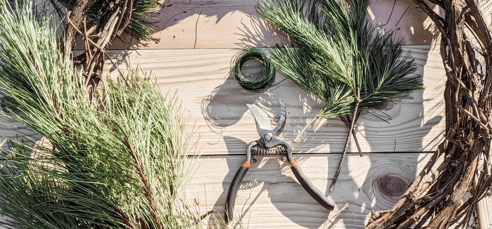 Pine branches, green gardening twine and secateurs displayed on the wooden surface.