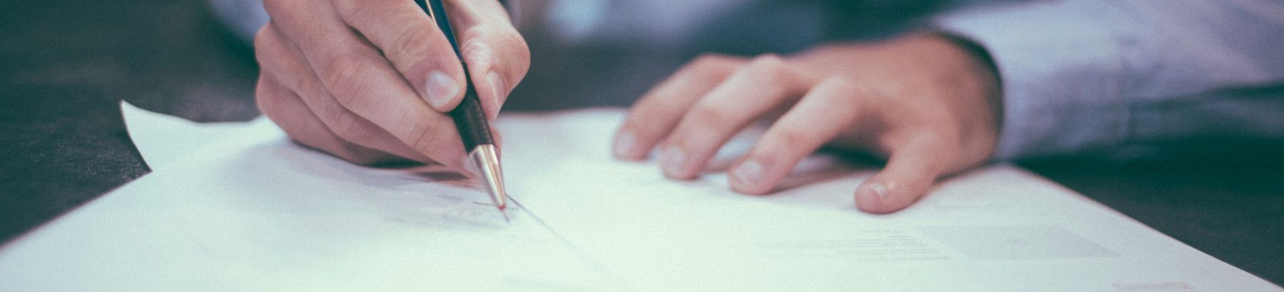 Close up of person signing documents.