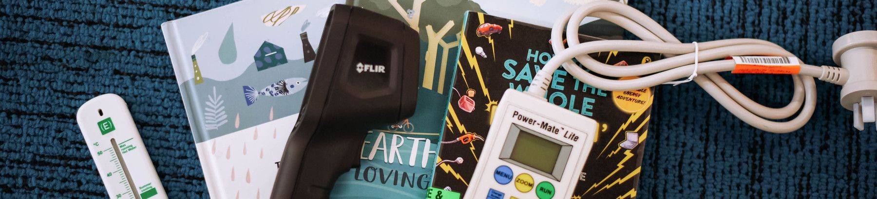 Thermometer, thermal imaging camera and a Power Mate Lite placed on top of library books on carpet.