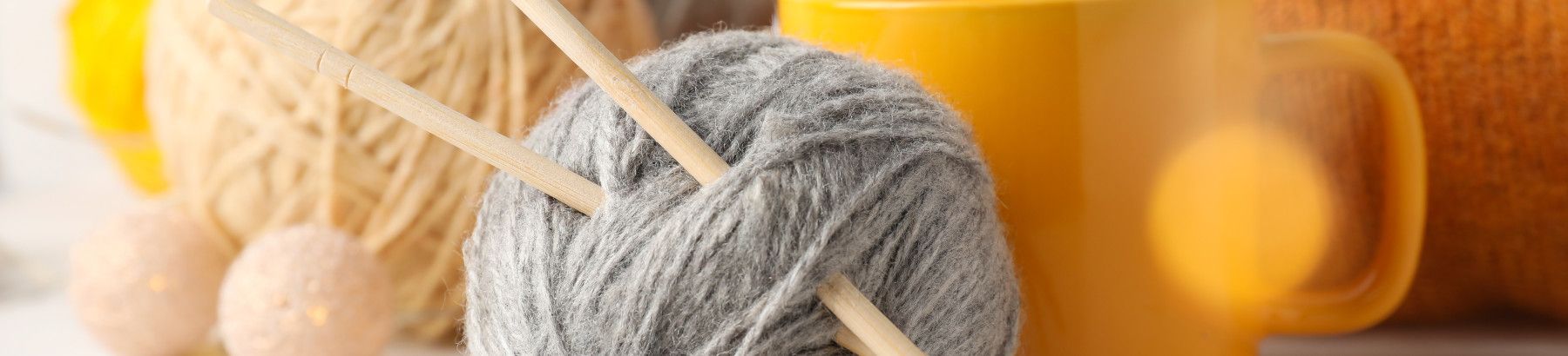 Balls of wool, a knitting needles and a mug on a table.