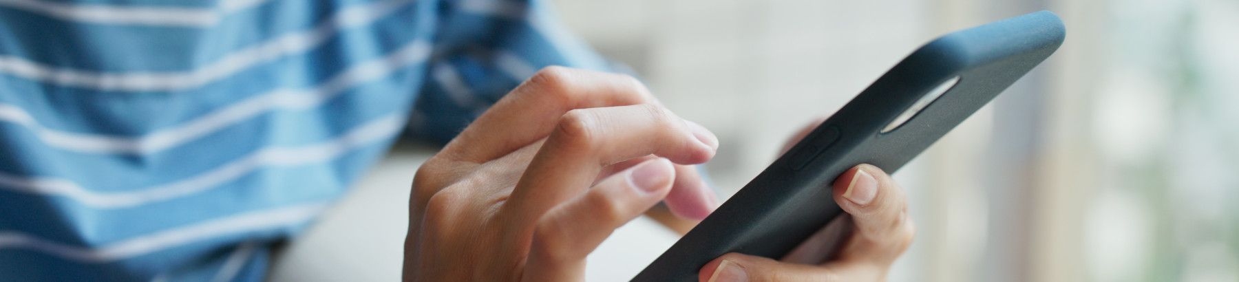 Closeup of person's hands using a mobile phone.