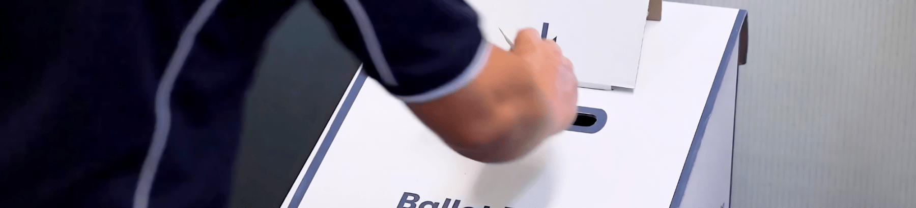 Person casting a ballot in a ballot box.