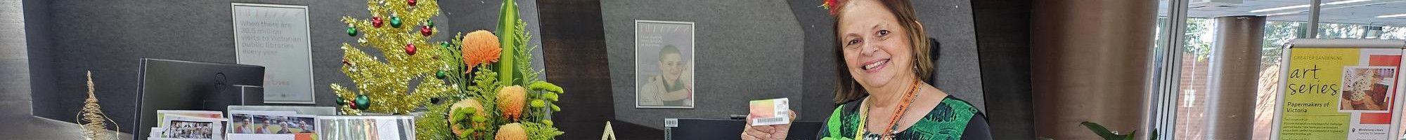 Staff member at the Dandenong Library service desk holding a membership card.