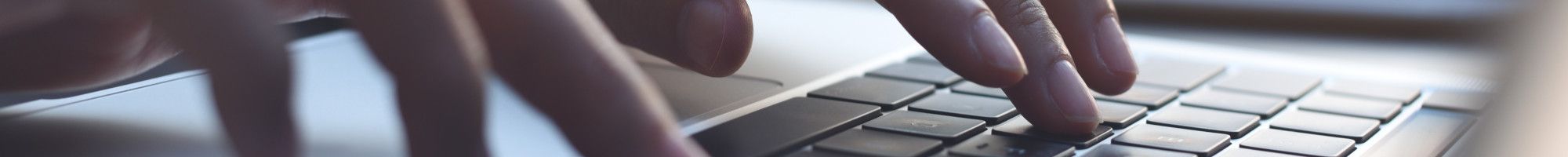 Closeup of a person's hands typing on a laptop.