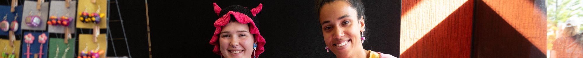 Two teenage girls sitting at the stall with creative colourful jewellery.
