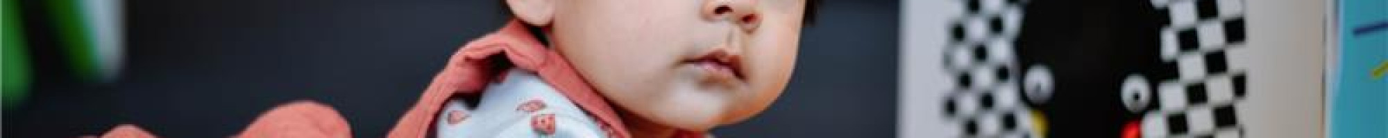 An infant on the floor with a board book.