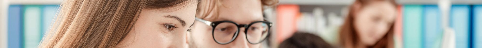 Students studying in a library with a laptop.