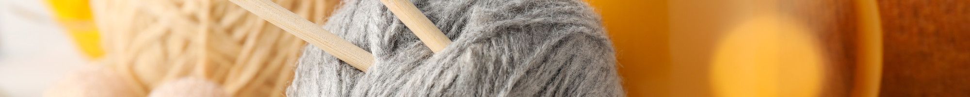 Balls of wool with knitting needles and a mug.