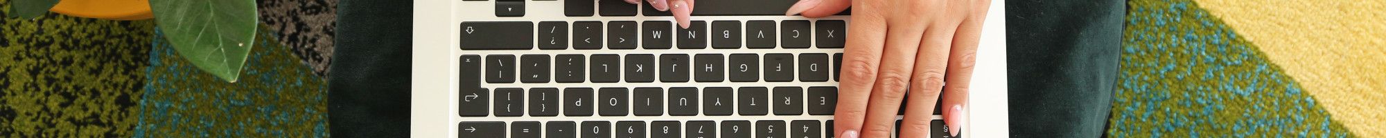 Shot from above of person using a laptop with plants on either side.