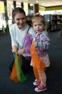 An adult and a child holding colourful fabric.