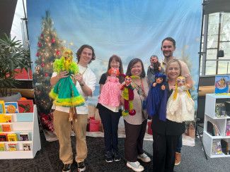 Four library staff members holding puppets with puppet entertainer Claire Everton.