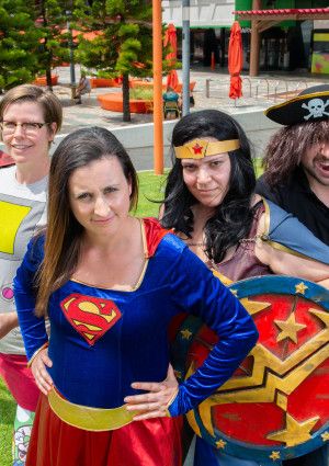 A small group of people dressed in costumes, for example, a superhero and a pirate.