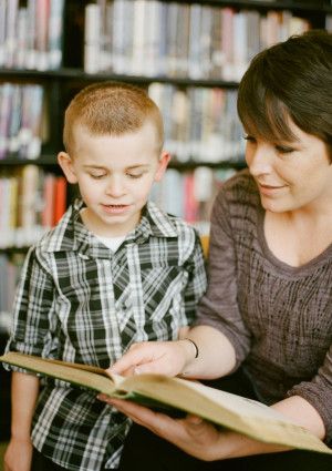 Parent reading with child in a library.