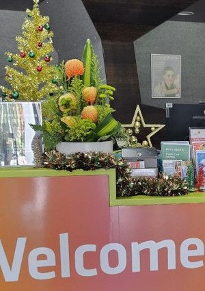 Staff member at the Dandenong Library service desk holding a membership card.