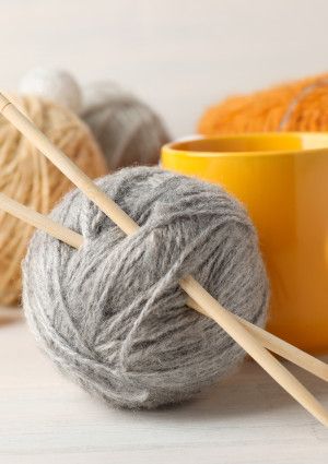 Balls of wool with knitting needles and a mug.