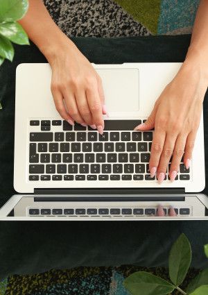 Shot from above of person using a laptop with plants on either side.